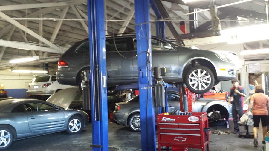 Cars raised on the blue lifts inside the garage with tools out mid job